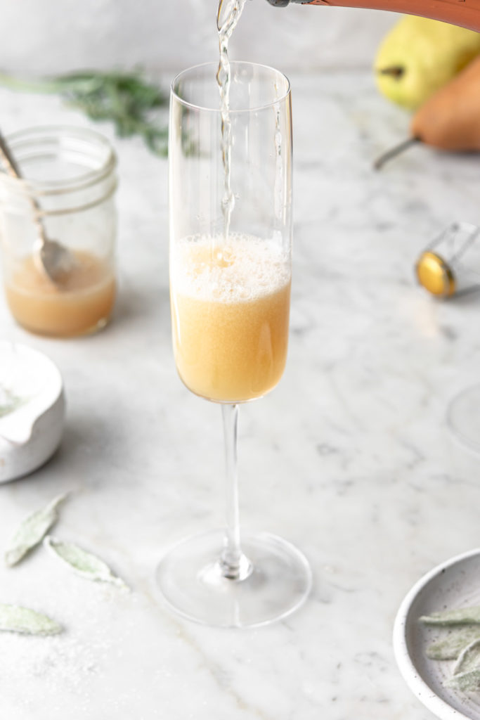pouring champagne into honey pear bellini