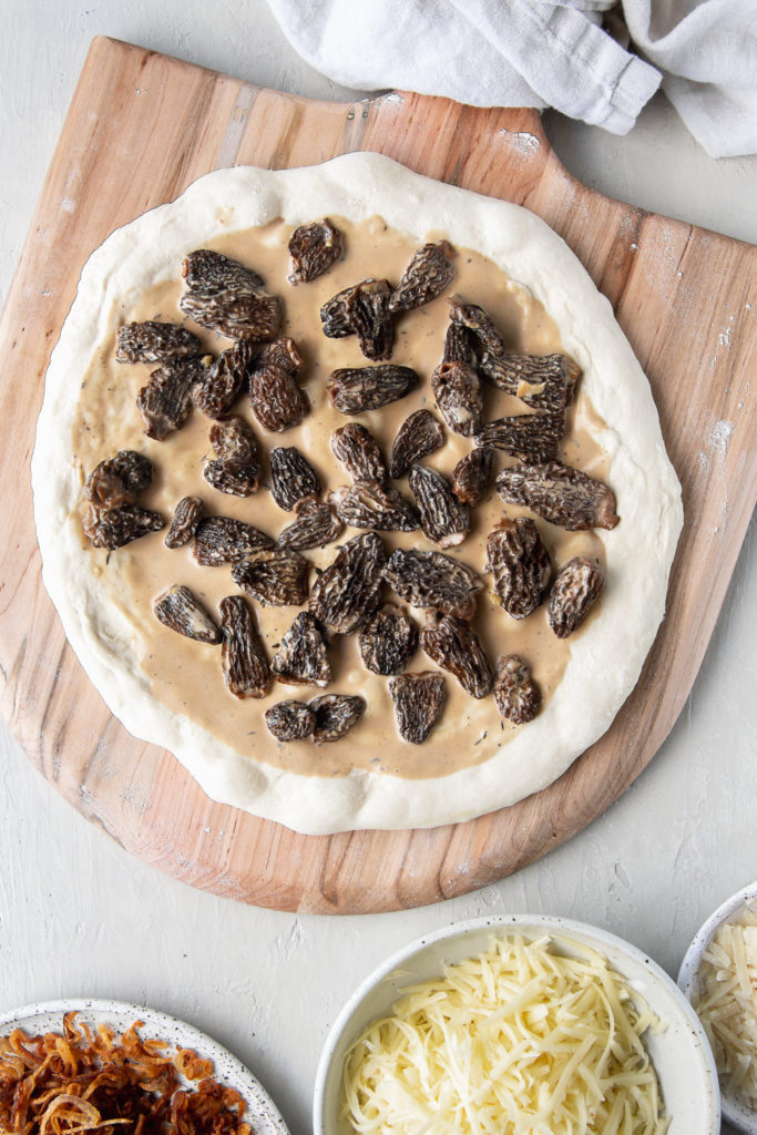 making the morel pizza with cream sauce, dough, fried shallots and cheese