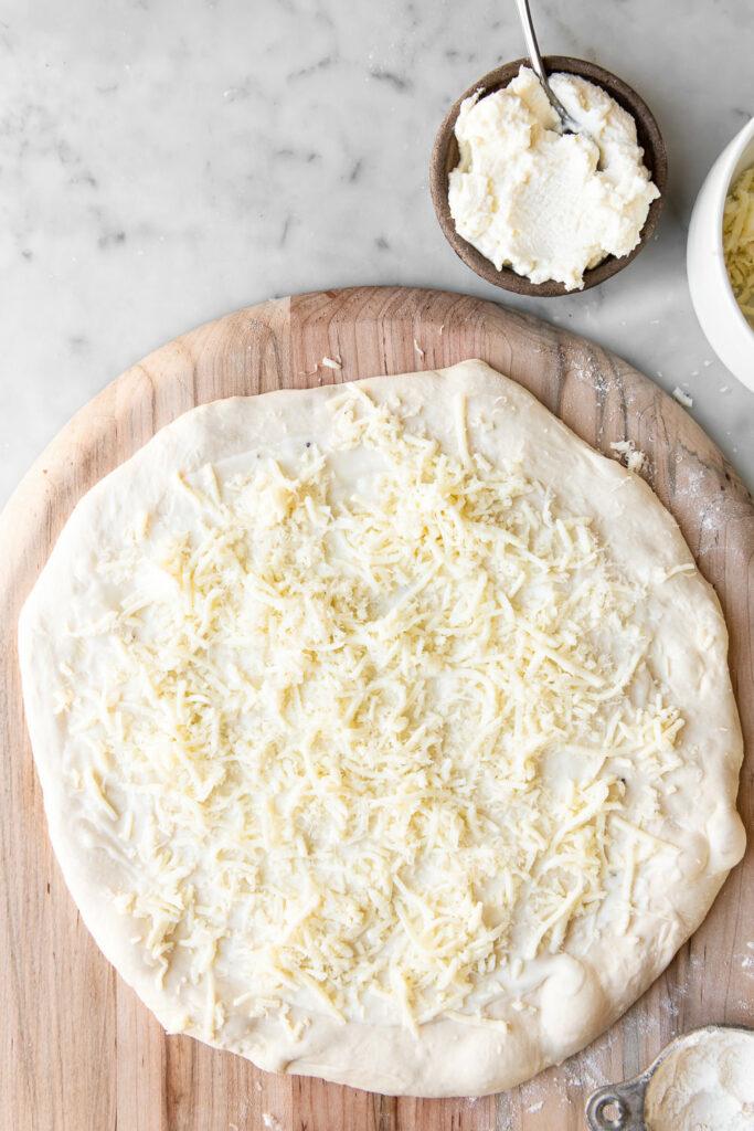 adding mozzarella and parmesan to pizza