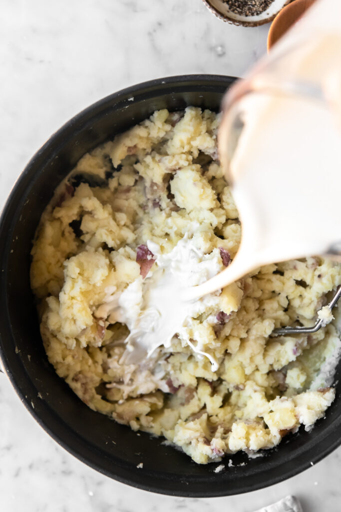 adding cream to mashed red potatoes